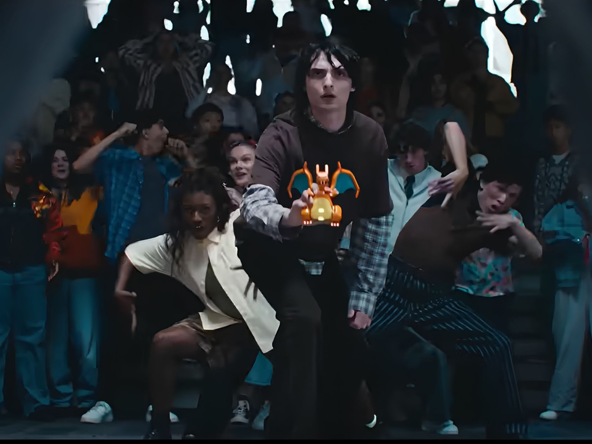 Finn Wolfhard holding a LEGO Charizard before a crowd.