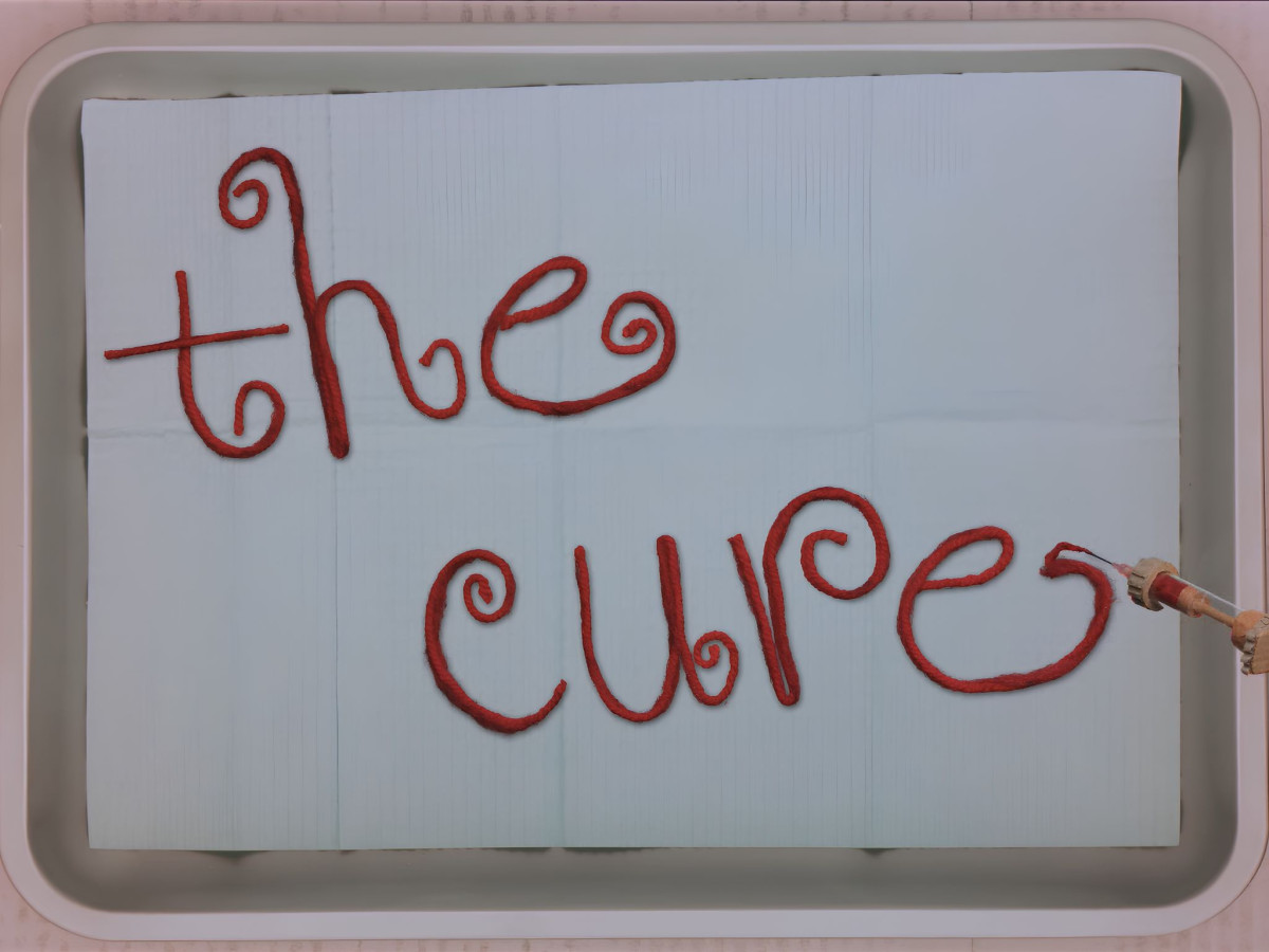 Red yarn spelling "the cure" next to a syringe.