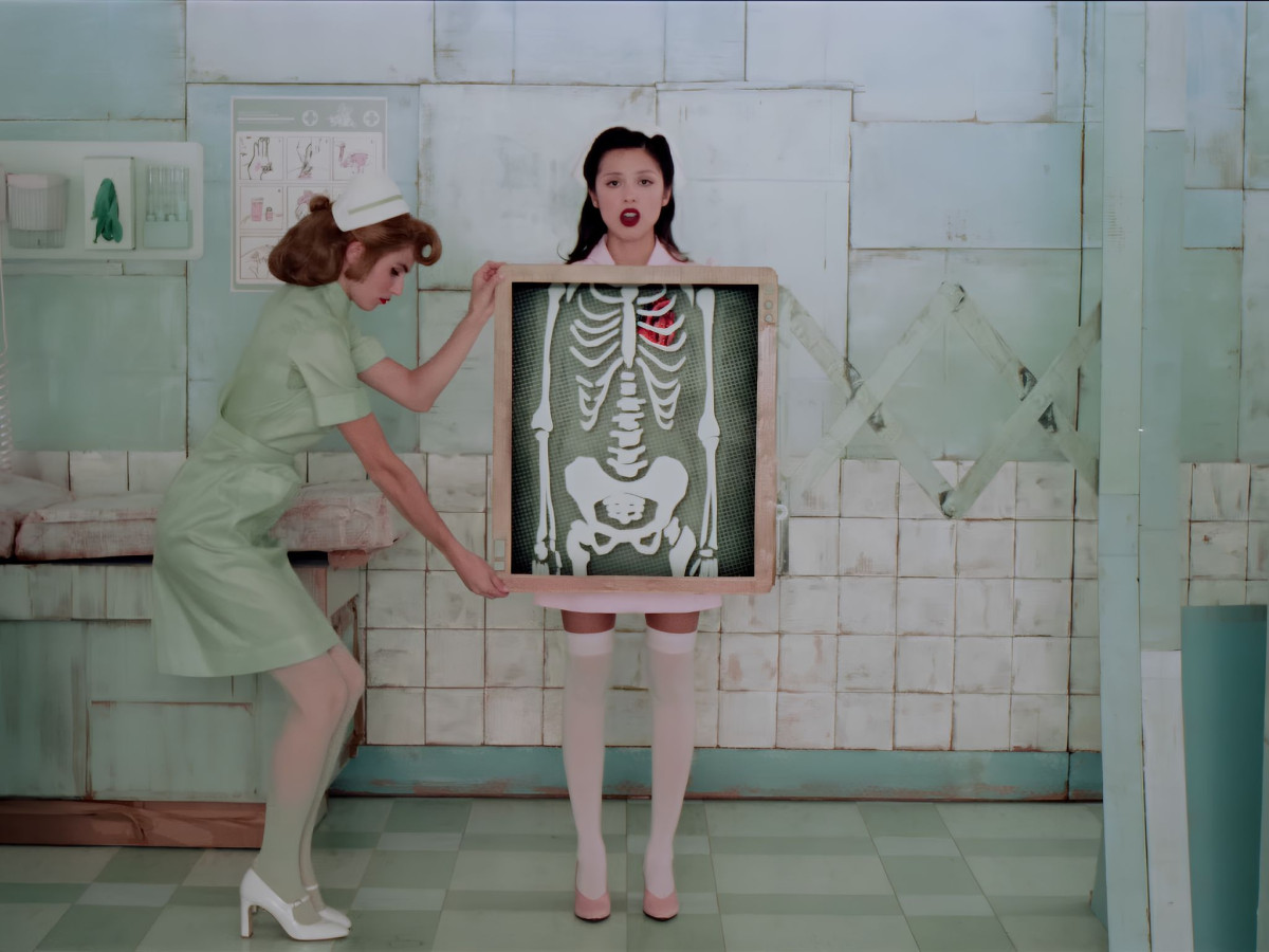 Nurse holding a framed skeleton graphic in front of Olivia Rodrigo.