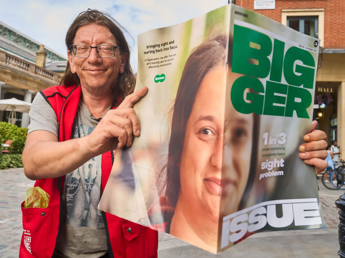 Vendor holding a giant edition of The BIGGER Issue magazine.