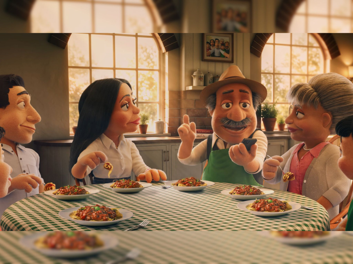 Dolmio puppet family eating spaghetti around a checkered table.