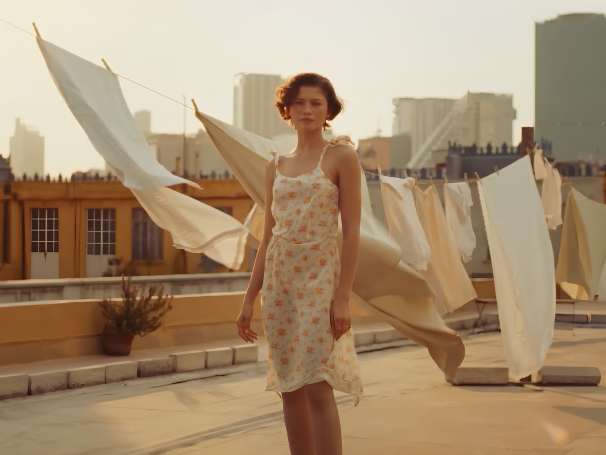Zendaya standing on a rooftop near hanging white laundry.