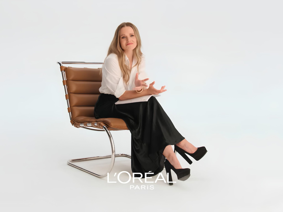Kristen Bell sitting in a brown chair talking animatedly.