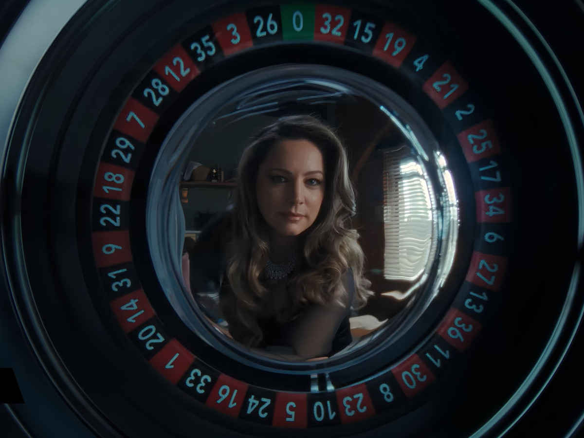 Woman staring directly through the center of a roulette wheel.