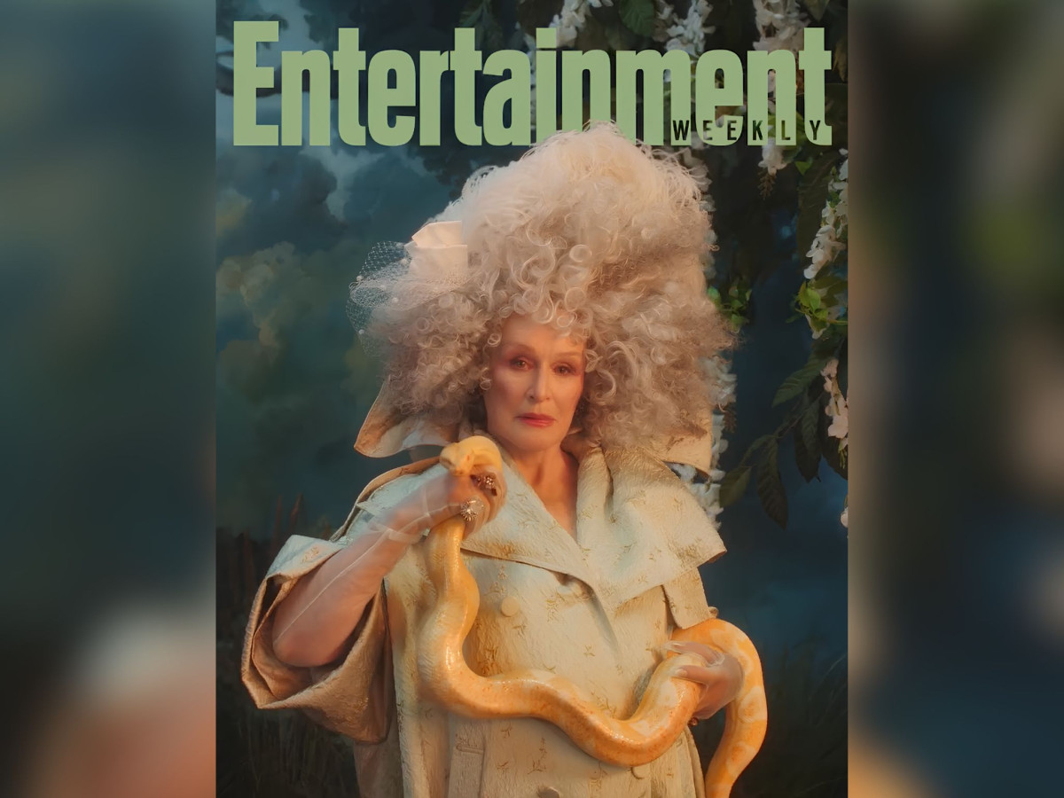 Glenn Close with large white hair holding a yellow snake.