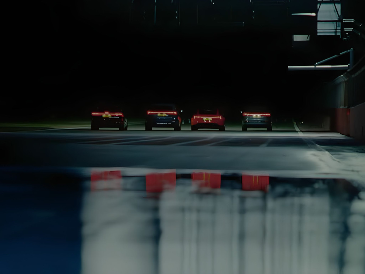 Four Audi cars lined up at night reflecting in puddle.
