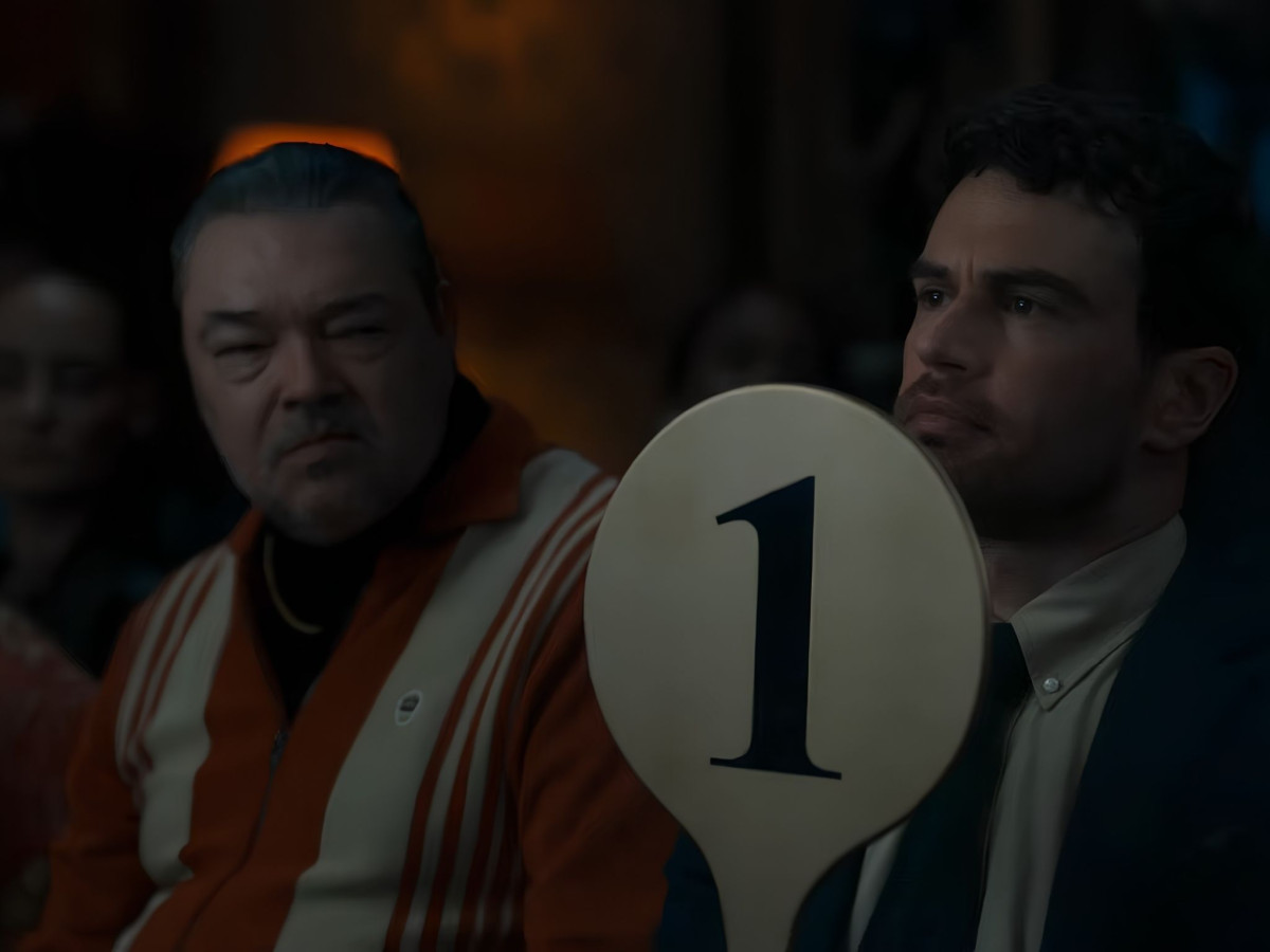 Theo James holding up an auction paddle marked with the number 1.