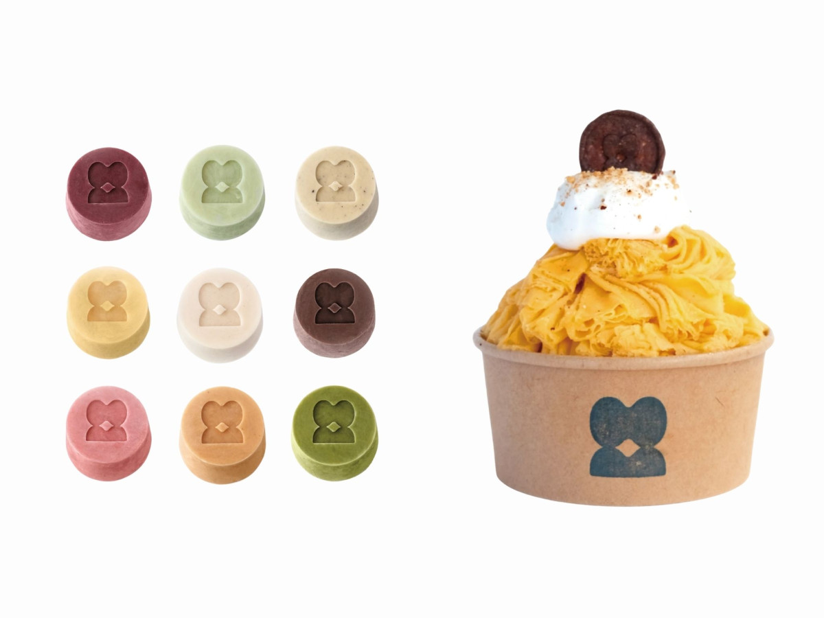 Colorful embossed logo tokens beside a yellow shaved ice cup.
