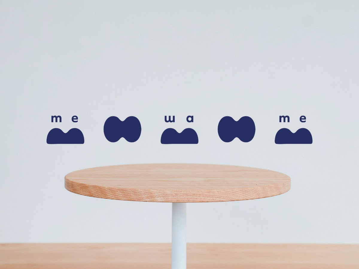 Abstract blue logo shapes spelling mewame above a wooden table.