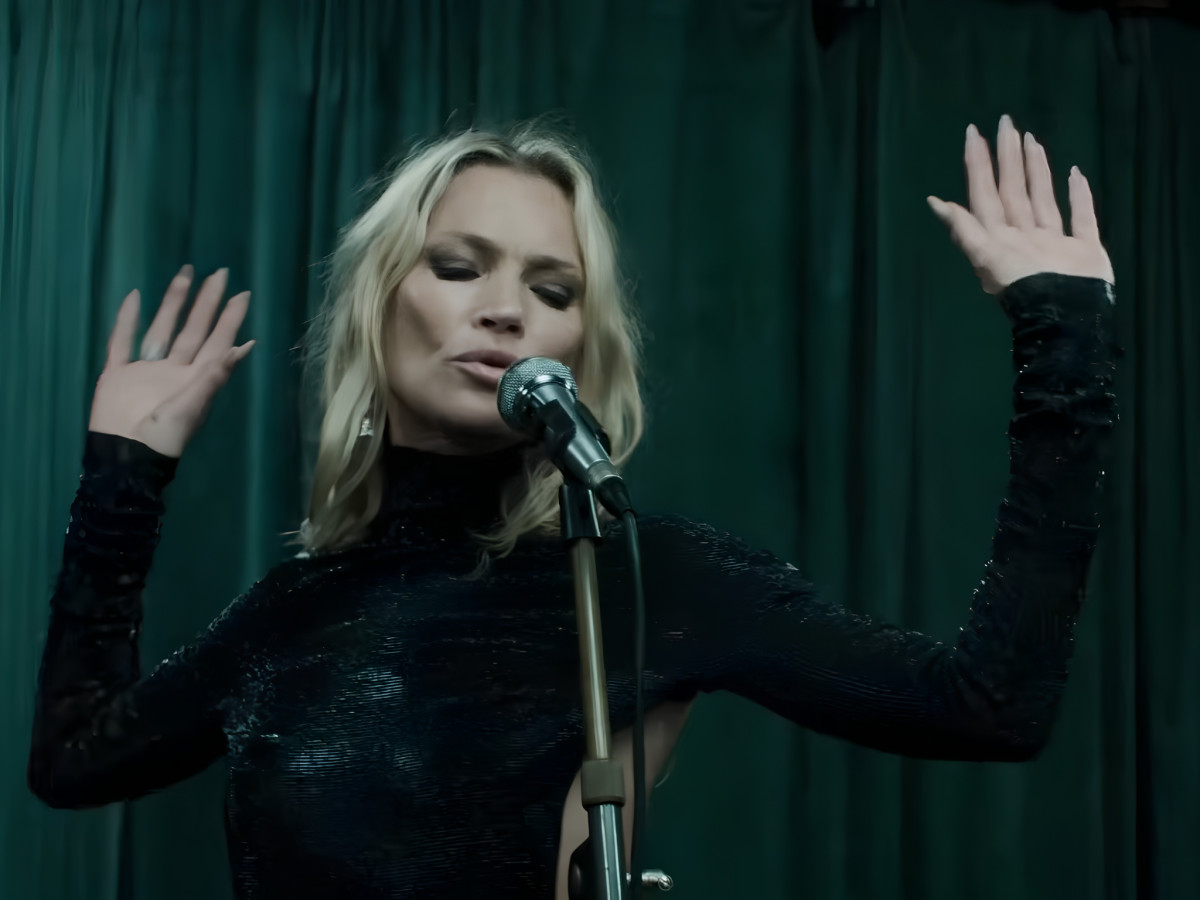 Kate Moss singing into a microphone.