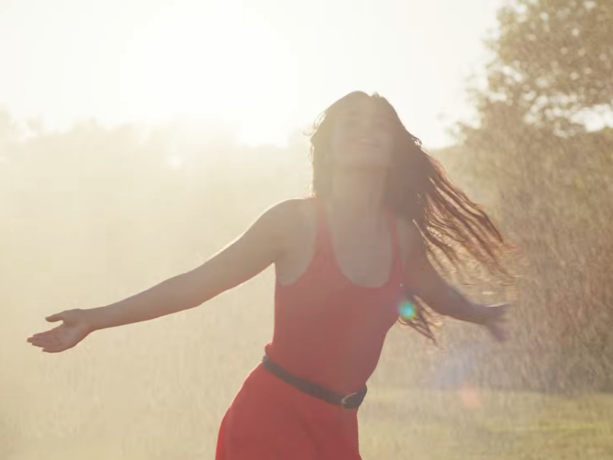 Woman in a red dress spinning in the sun.