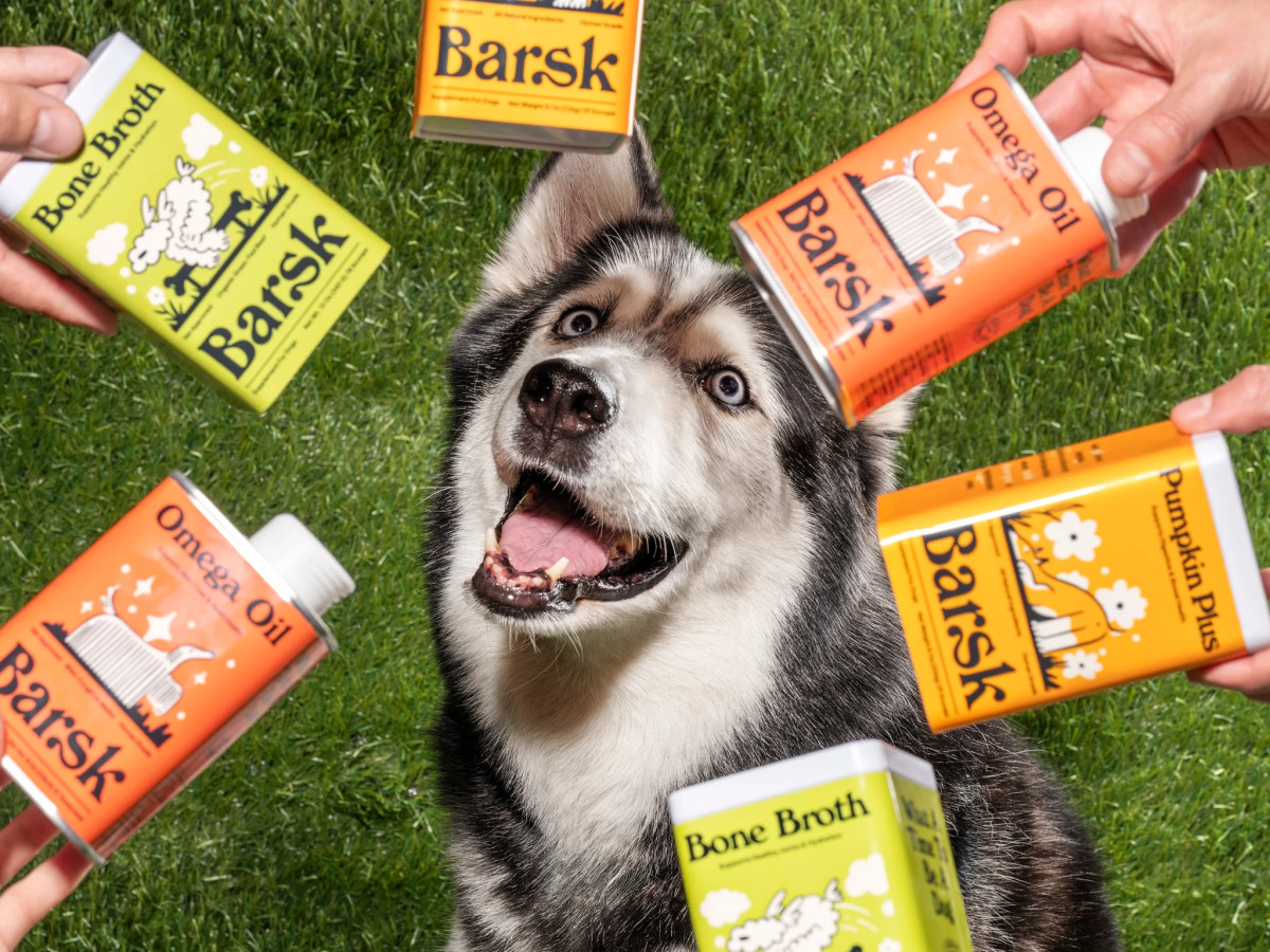Husky surrounded by hands holding Barsk supplement containers.