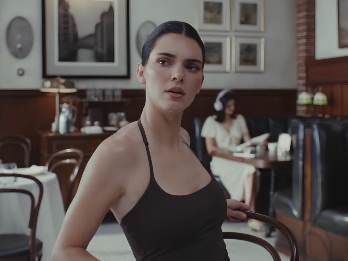 Kendall Jenner sitting in a restaurant wearing black top.
