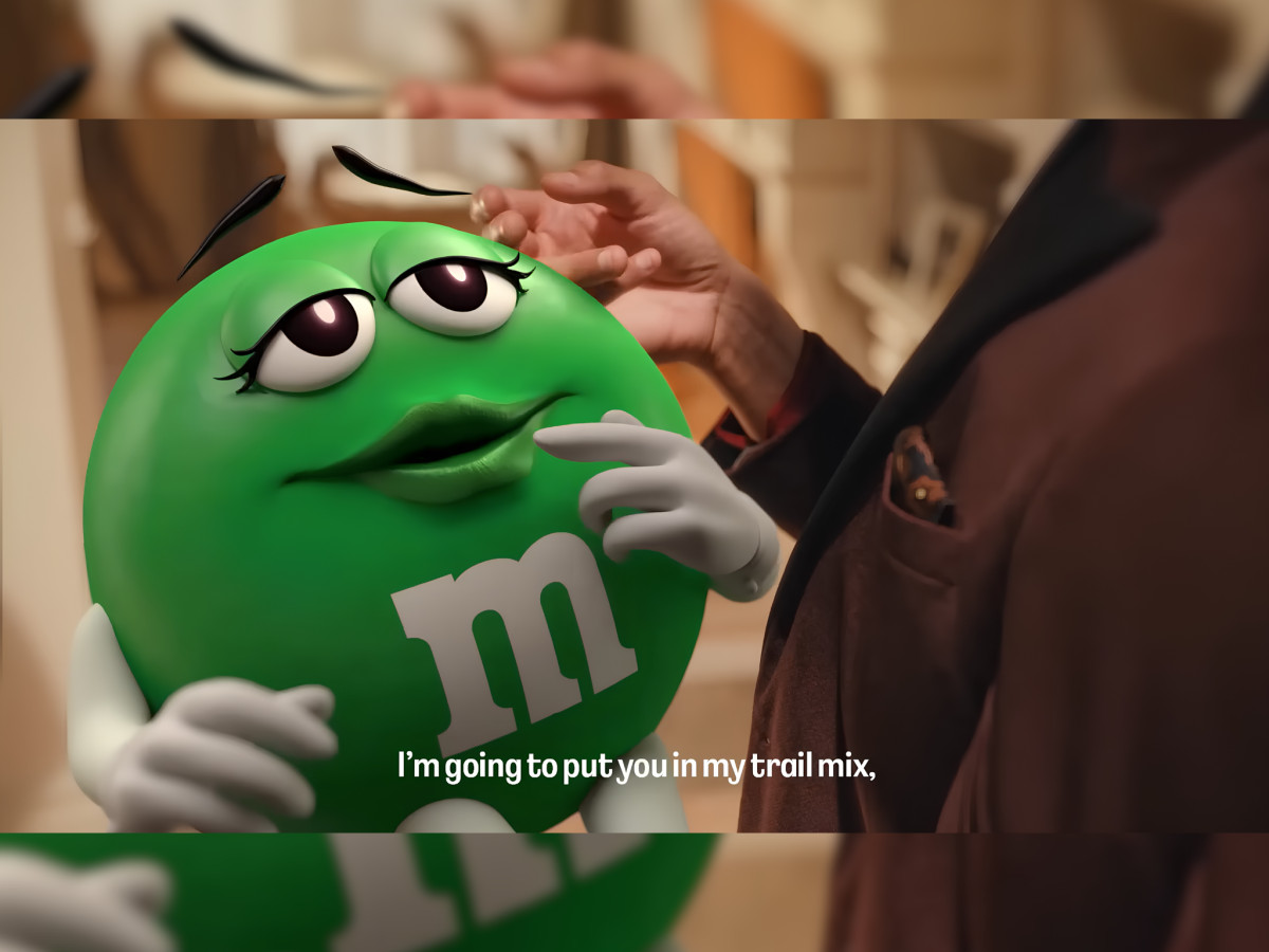 Close-up of Green M&M with trail mix subtitle.