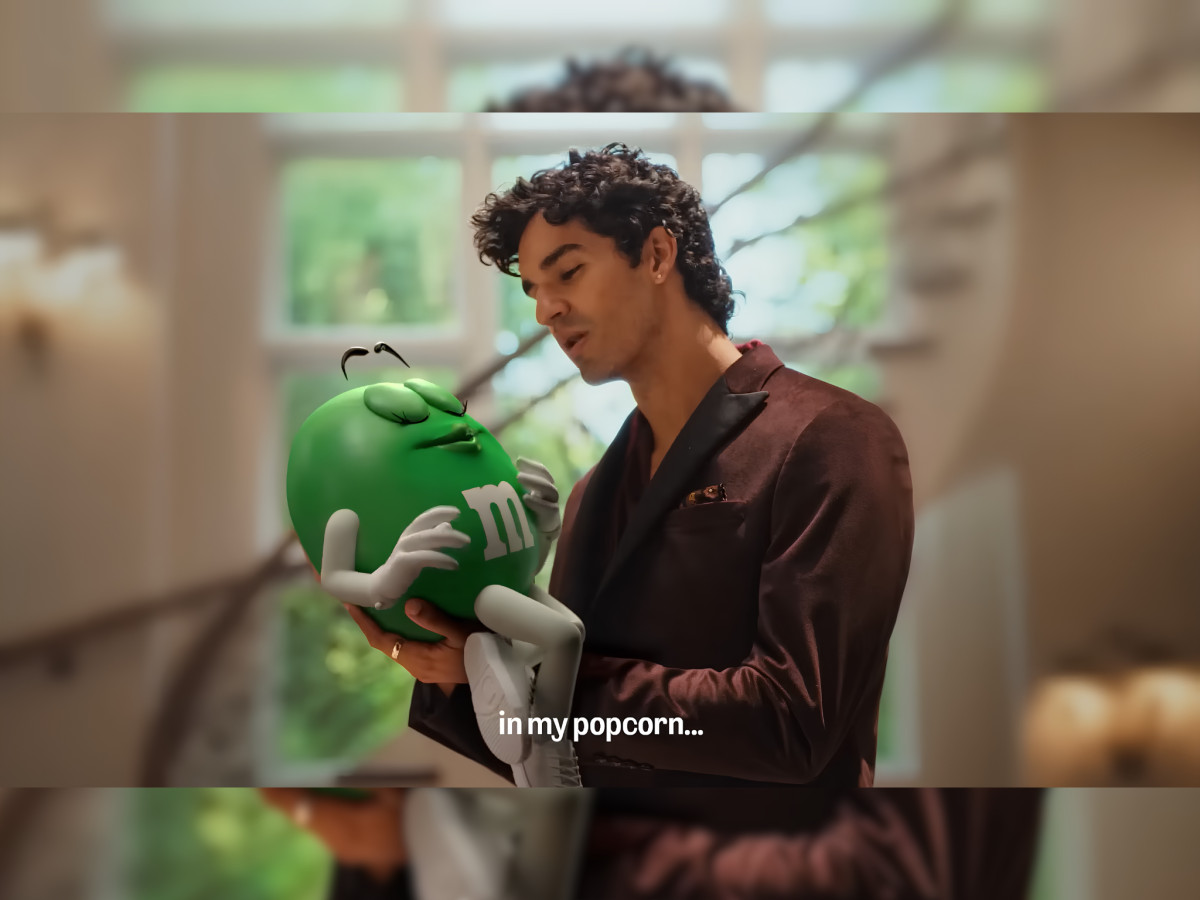 Man in suit holding Green M&M with popcorn subtitle.