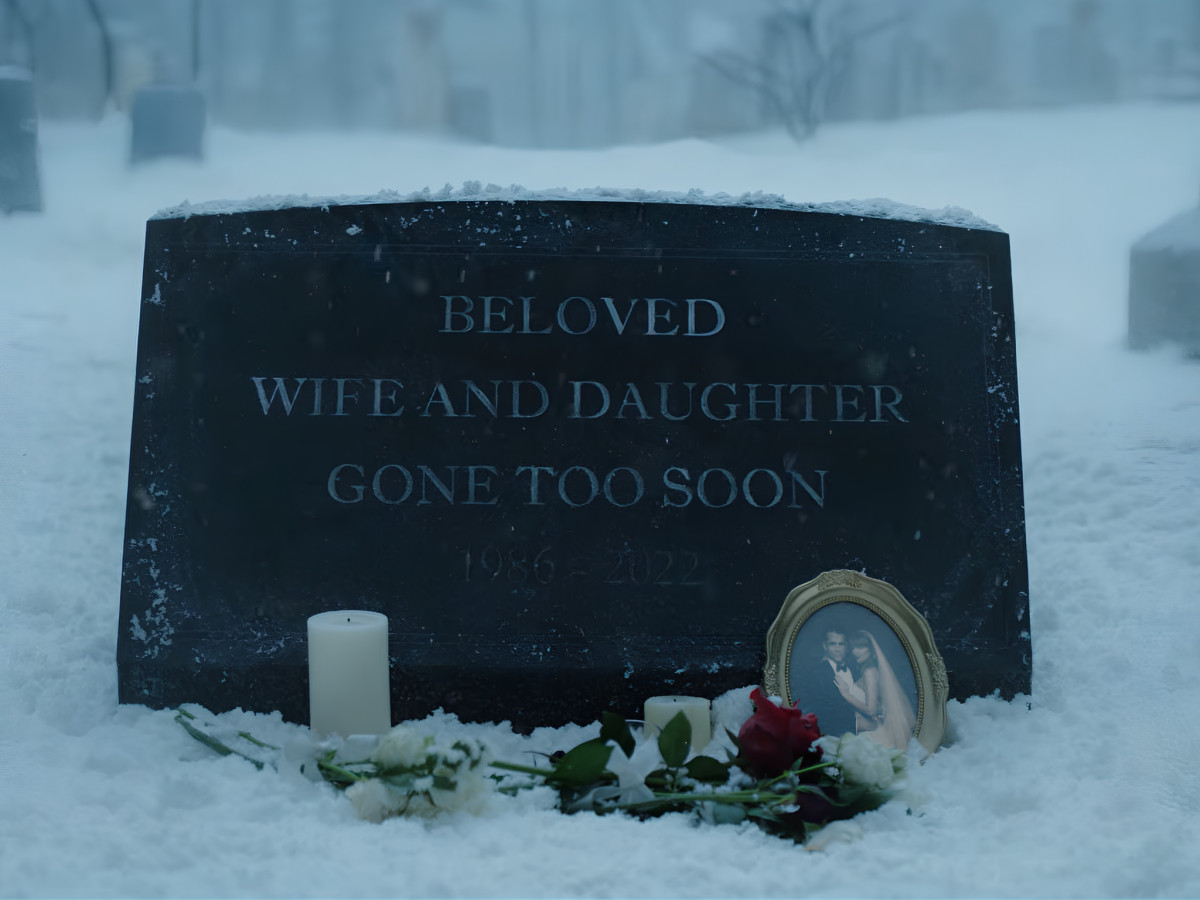 Snow-covered gravestone with flowers and a framed photo.