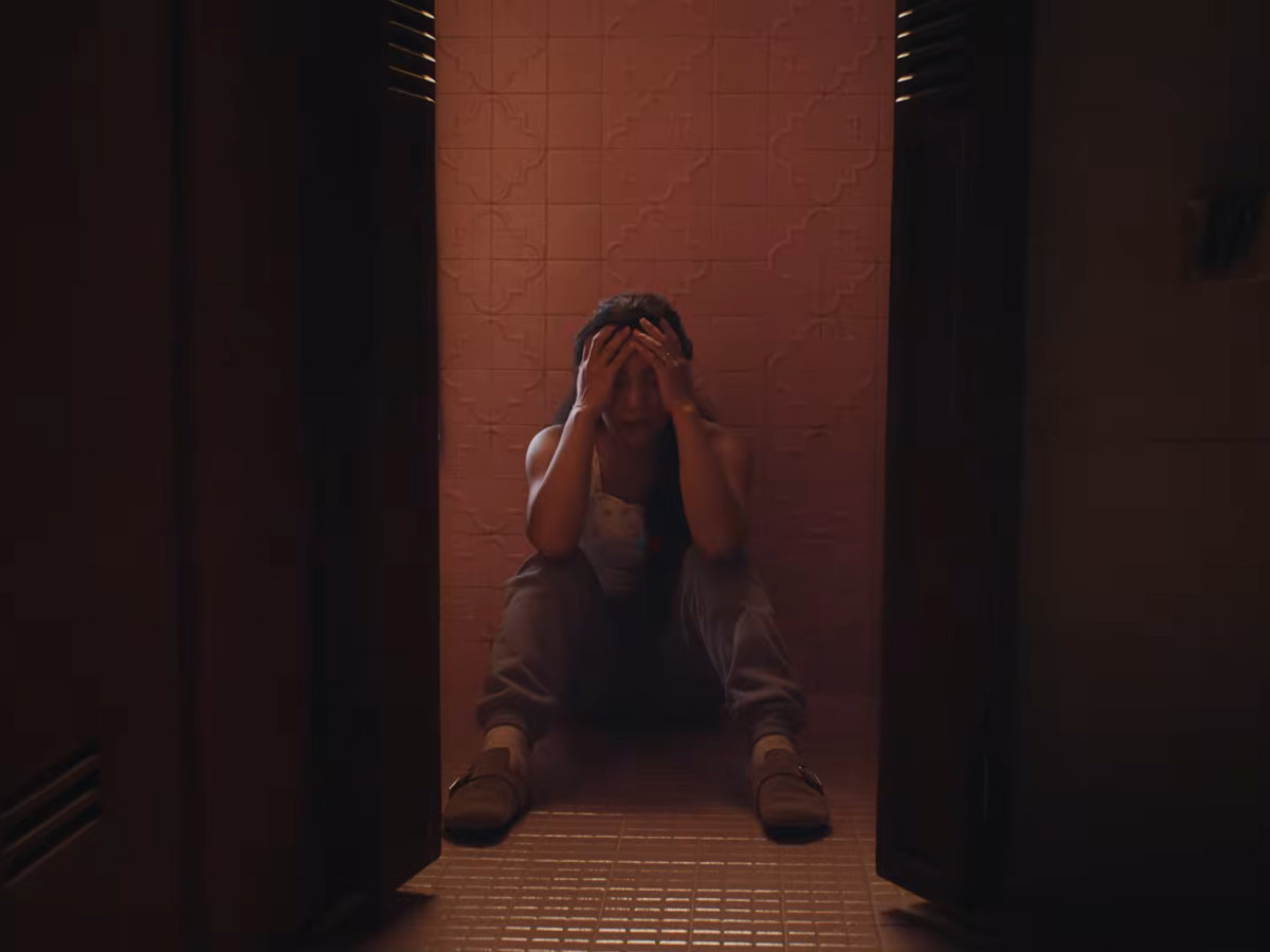 Overwhelmed woman sitting on the floor holding her head.