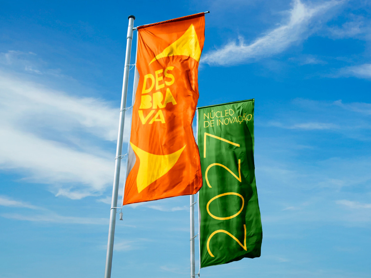 Orange and green Desbrava branded flags flying outdoors.