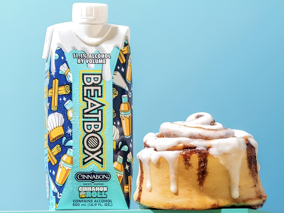 BeatBox Cinnamon Roll carton placed next to a frosted Cinnabon cinnamon roll.