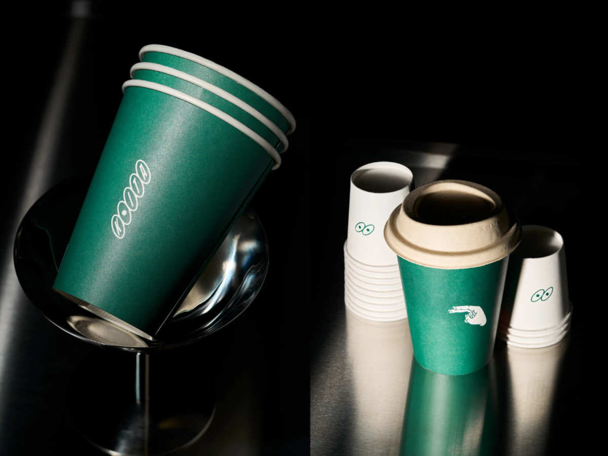 Green KOITA takeaway coffee cups with branded illustrations.