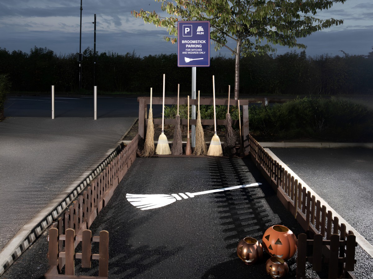 Aldi broomstick parking bay with custom signage and wooden rack.