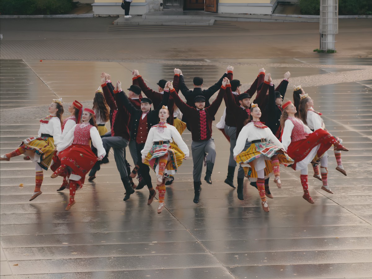 Estonian folk dancers performing choreography in open square.