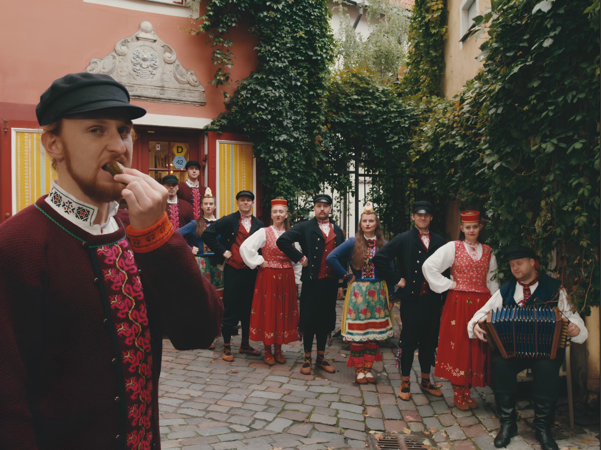 Folk dancers in traditional clothing posing in cobblestone alley.