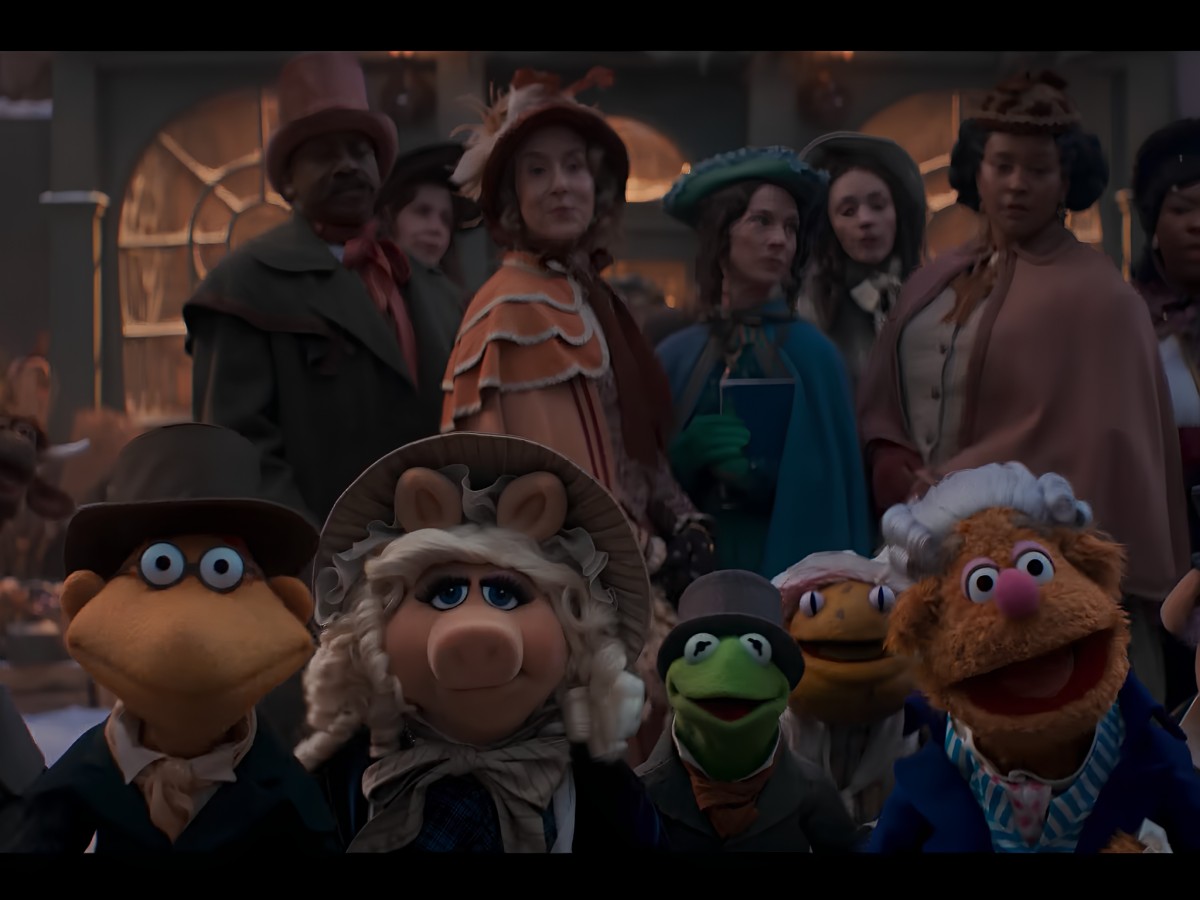 Muppet characters in Victorian costumes amidst a town crowd.