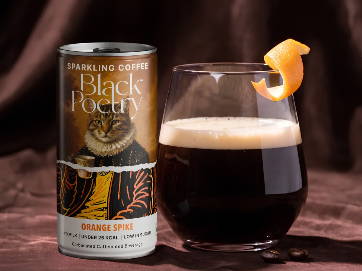 Black Poetry Orange Spike can beside garnished glass of coffee.