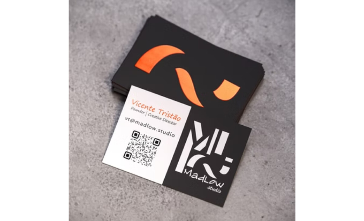 Two-sided MadLow Studio business card on a textured gray surface