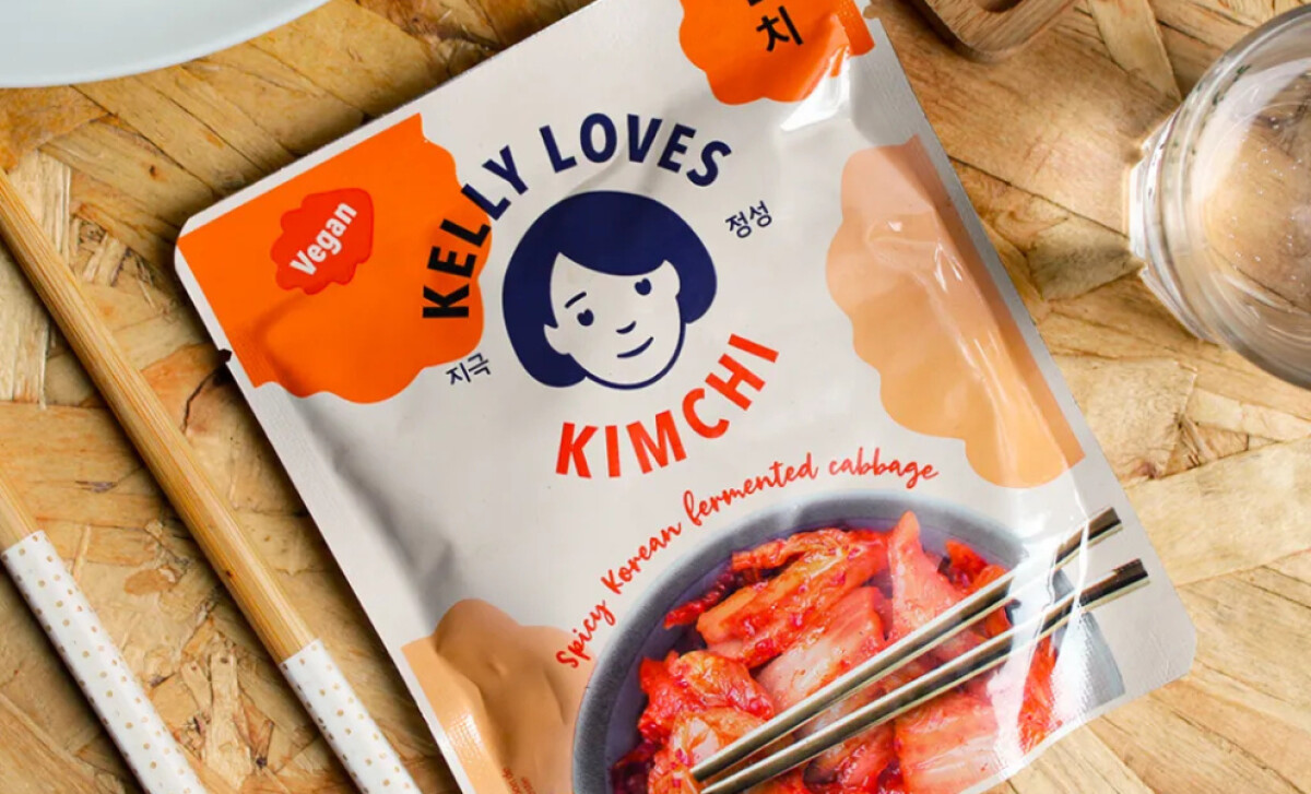 Pack of Kelly Loves Kimchi with chopsticks on wooden table by Without Studio.