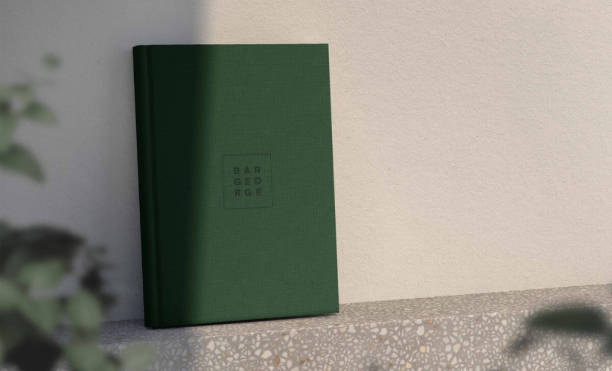 Bar George dark green hardcover book-style menu with embossed logo