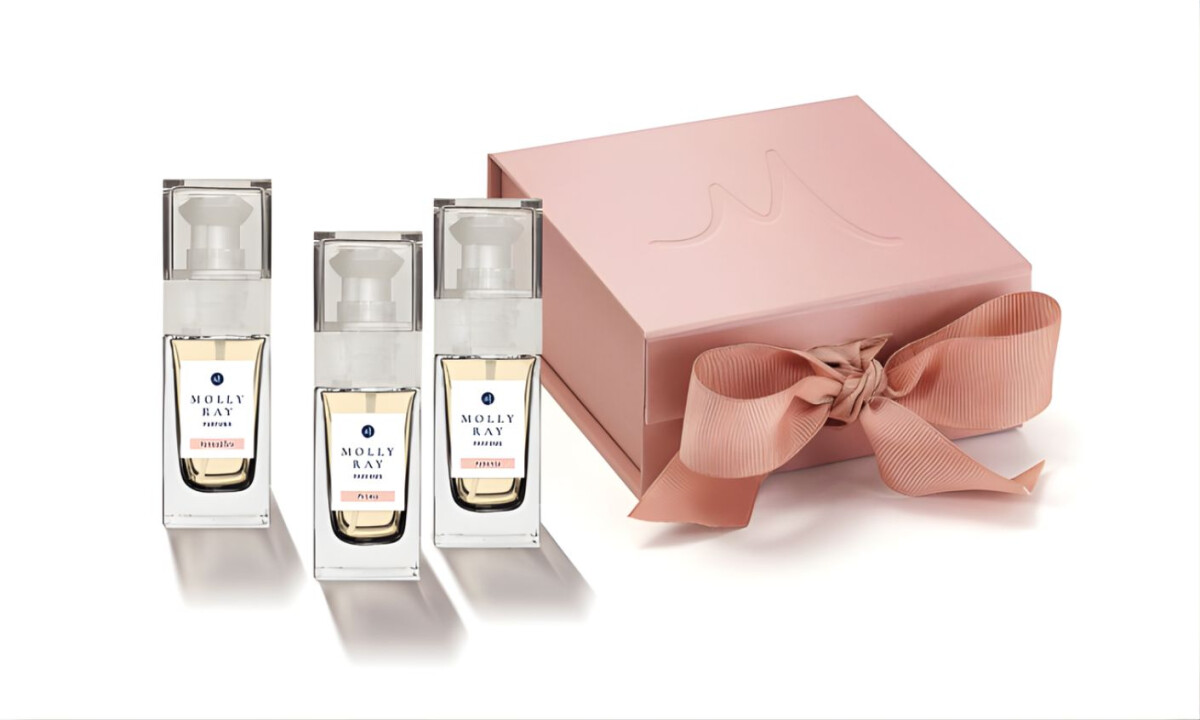 Blush gift box with ribbon closure alongside clear glass fragrance bottles