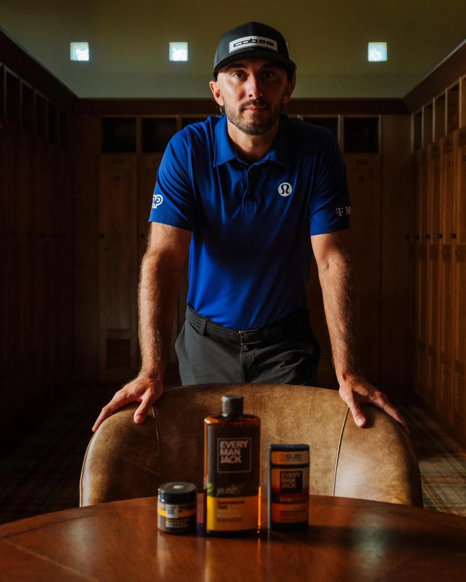 max-homa-emj-product-line Max Homa stands behind a chair with the Every Man Jack product line on a table in front of him.