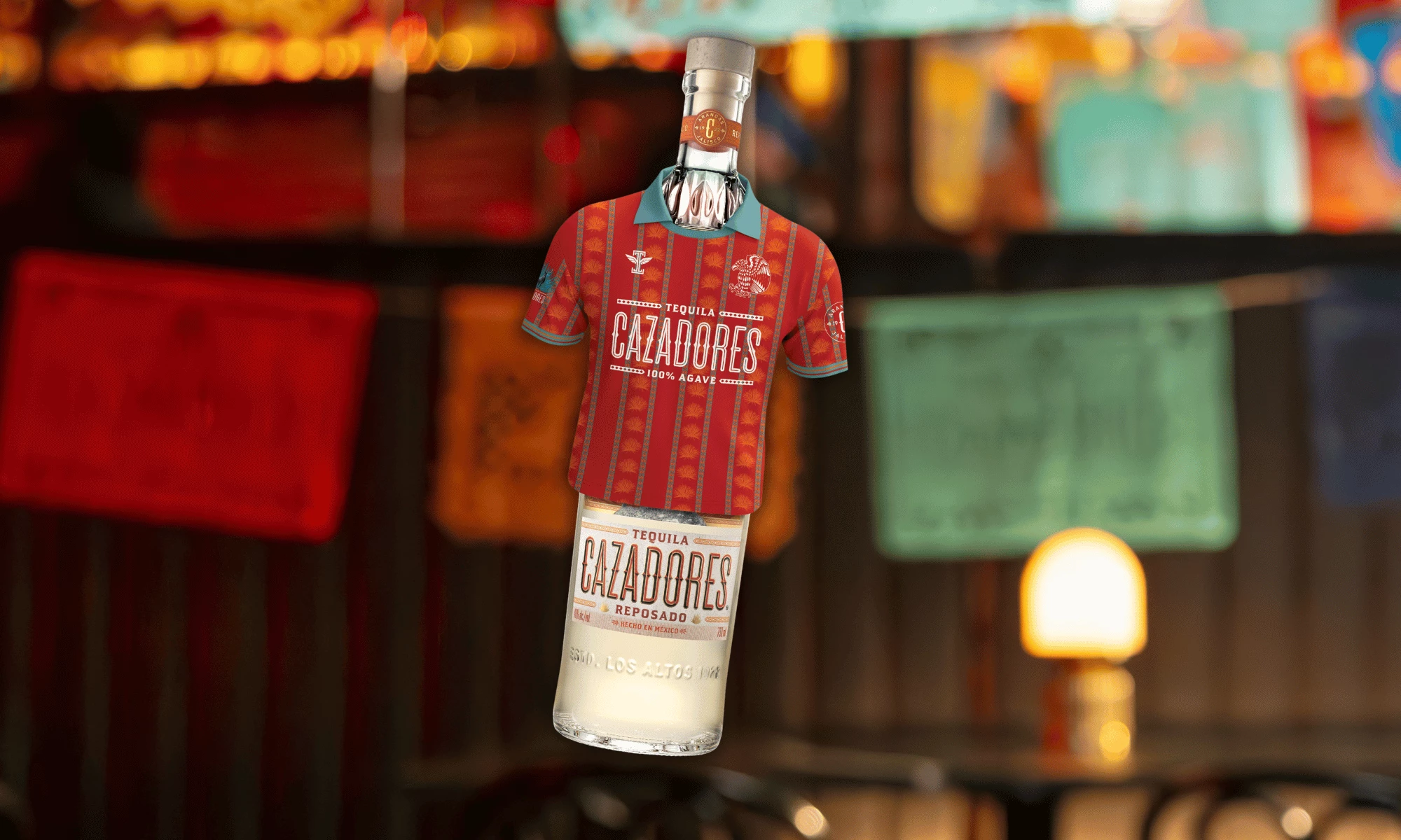CAZADORES Brings Fútbol Style to the Bottle A Tequila CAZADORES Reposado bottle wears a red fútbol jersey against a softly lit bar backdrop.