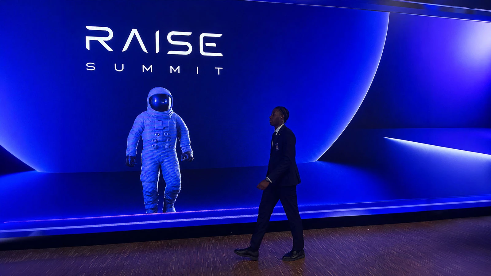Man walks by RAISE Summit 2026 LED screen on July 9, 2026. | Photo: DesignRush