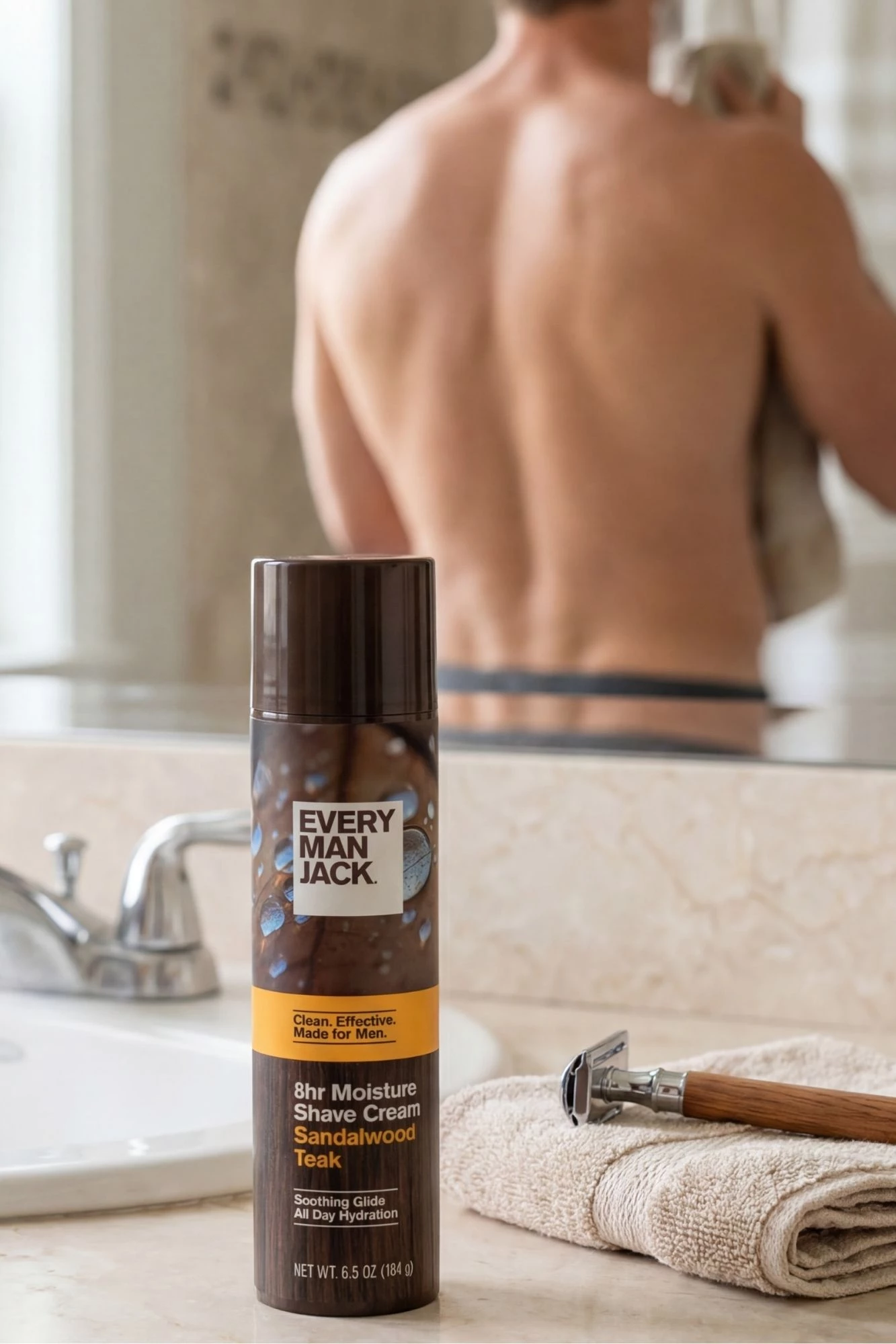 emj-shave-cream-sandalwood-teak Every Man Jack 8H Moisture Shave Cream Sandalwood Teak next to a shaver and a man in the background.