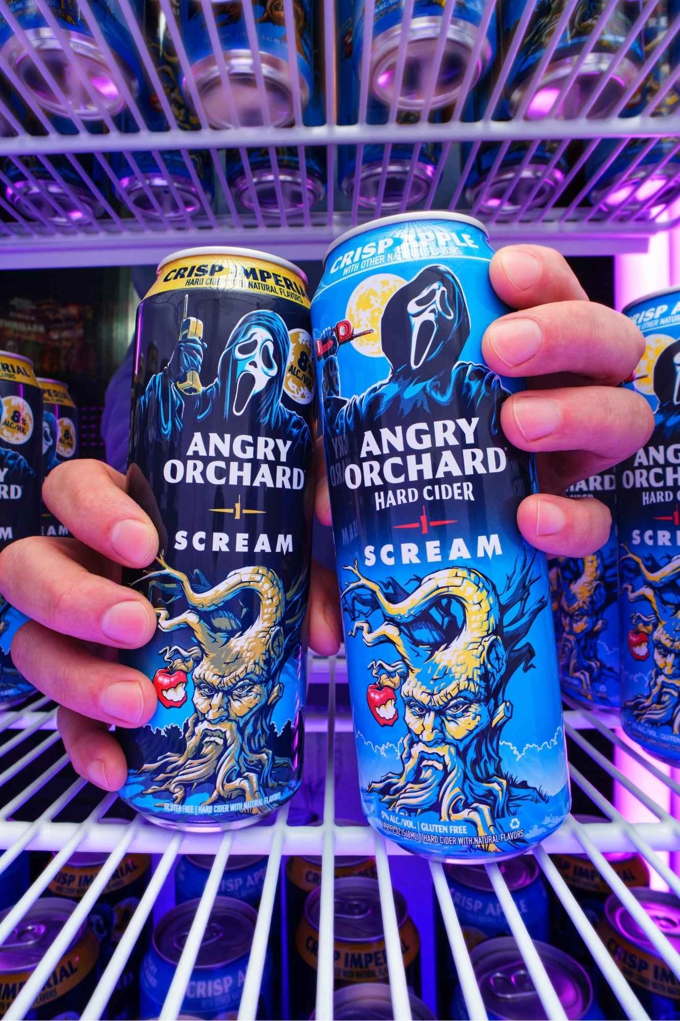 angry-orchard-ghost-face-cans Two hands grabbing the limited-edition Crisp Apple and Crisp Imperial cans in a fridge.