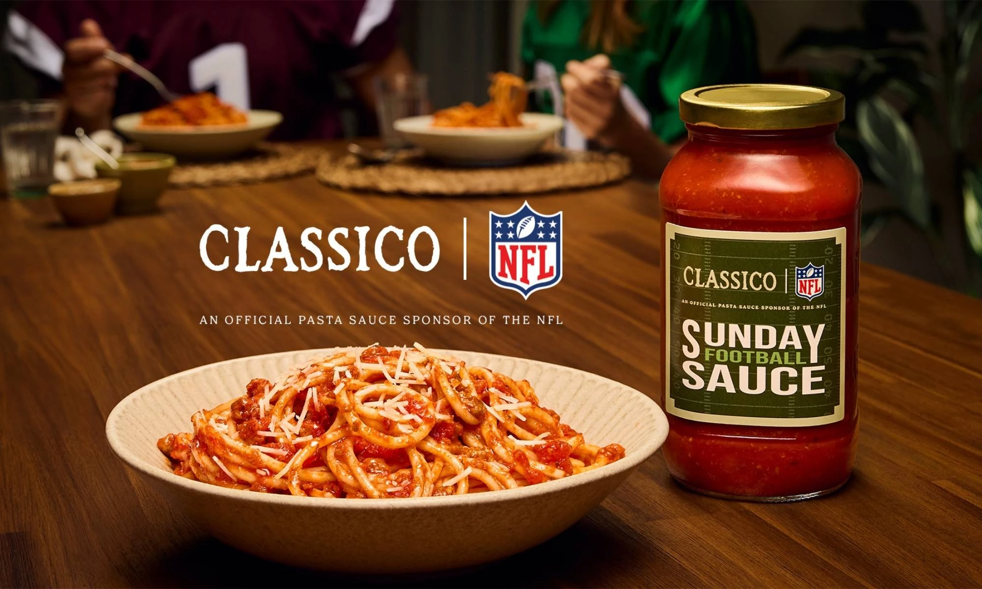 Classico Sunday Football Sauce on a dining room table with people and a bowl of pasta.