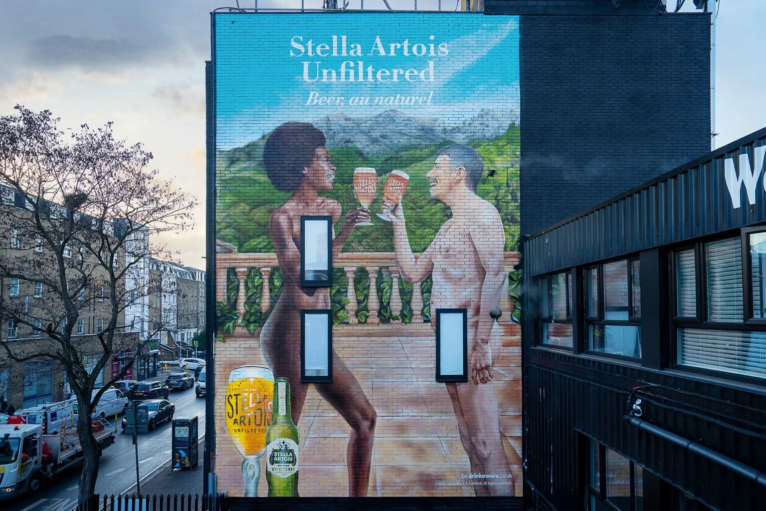Mural of two naked people looking at each other with Stella Artois beer in hand