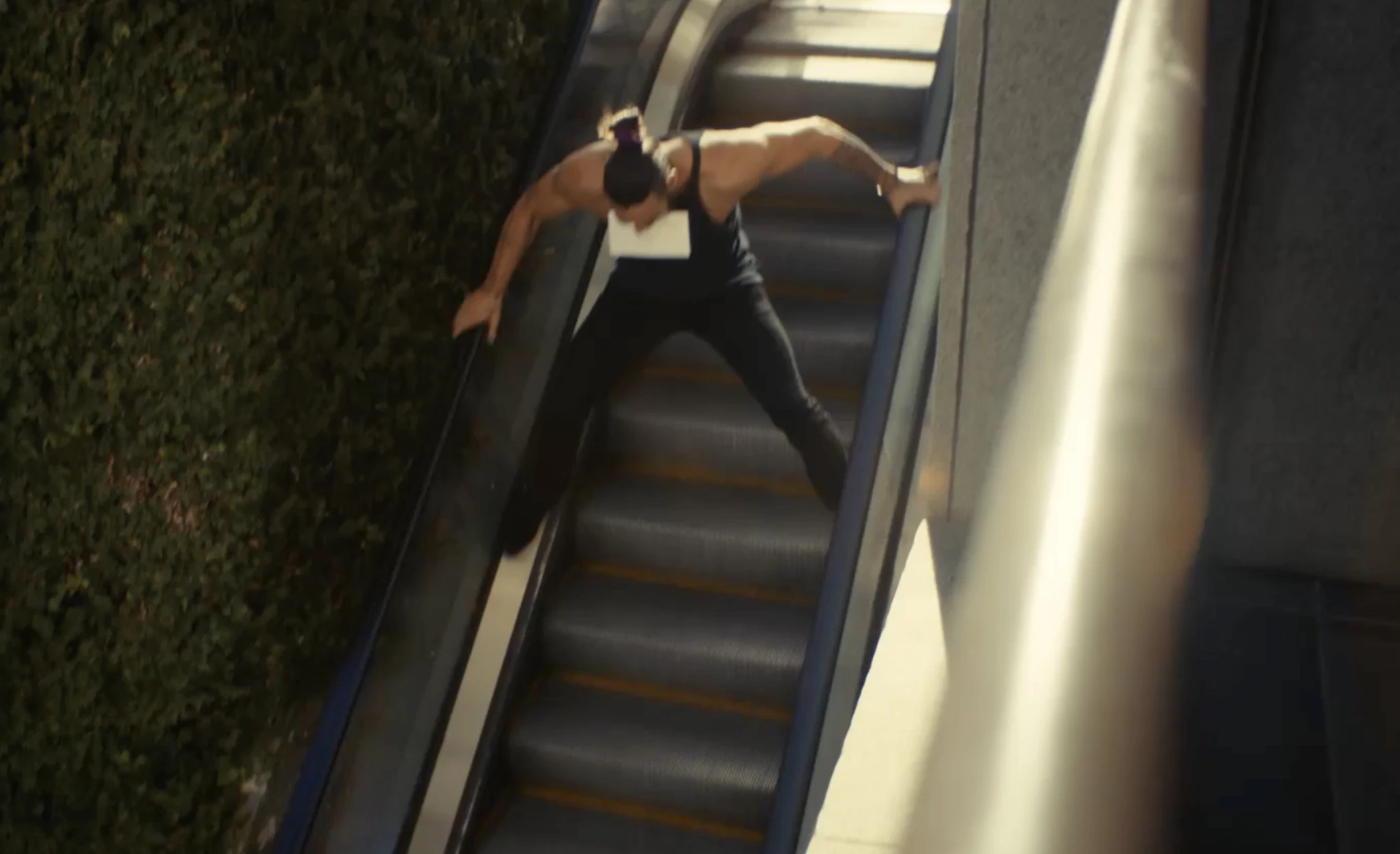 Jason Momoa slides down an escalator.