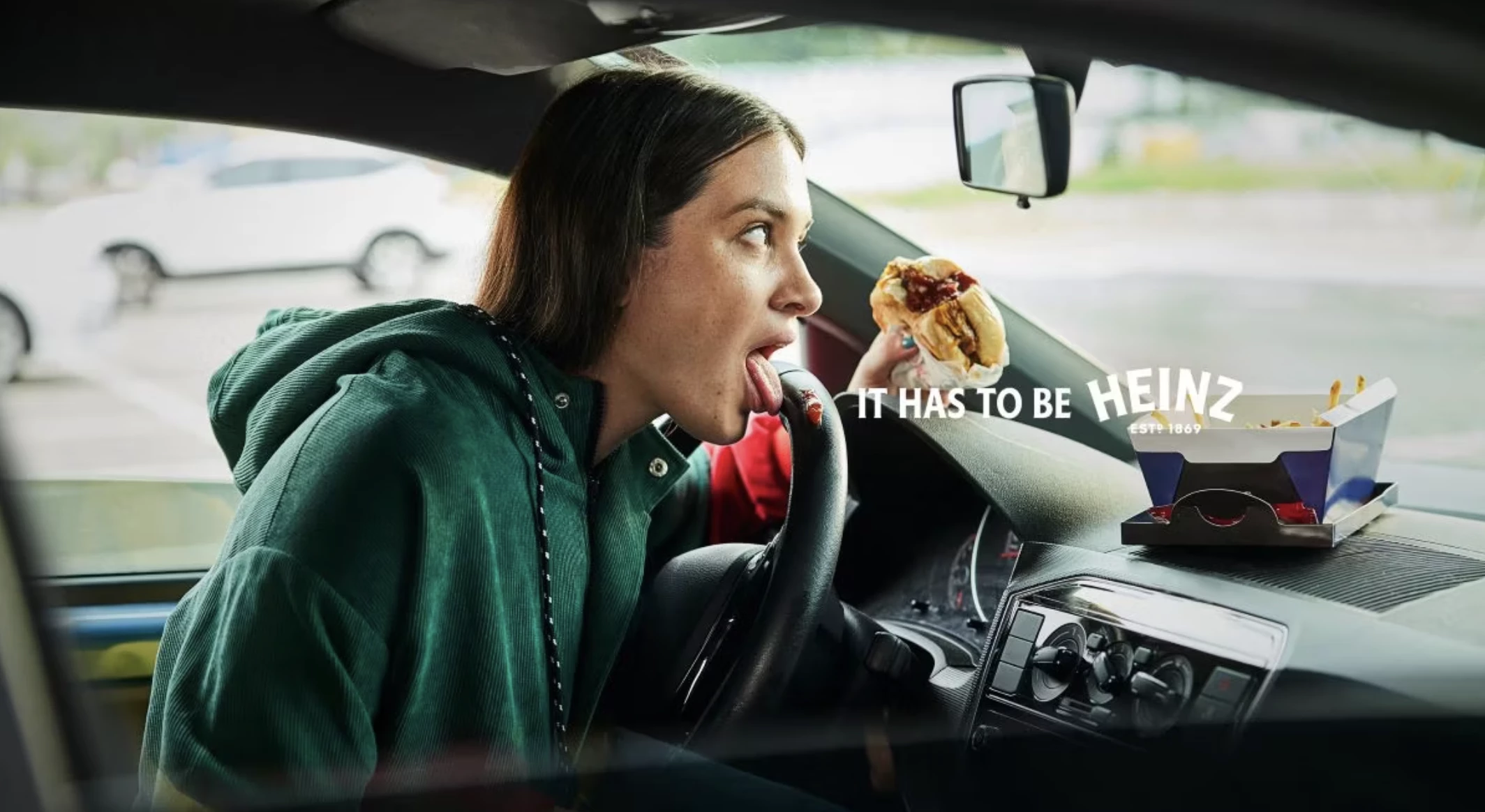 A woman licks Heinz off her steering wheel. | Source: Heinz