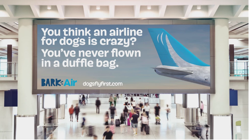 A BARK Air billboard reads, "You think an airline for dogs is crazy? You've never flown in a duffle bag."
