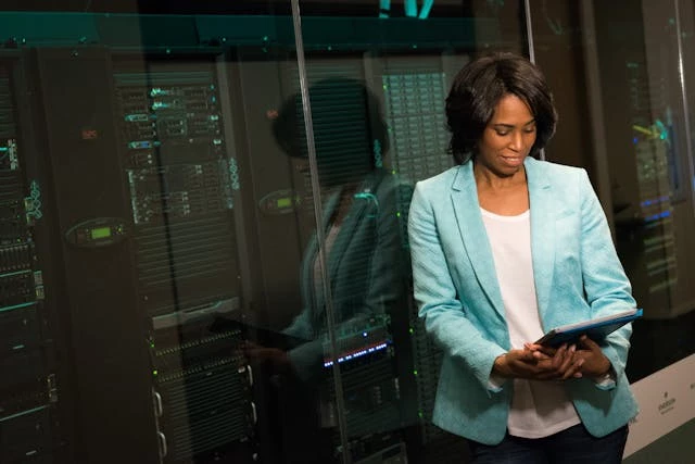 Woman with servers behind her assessing the types of backups available Woman with servers behind her assessing the types of backups available