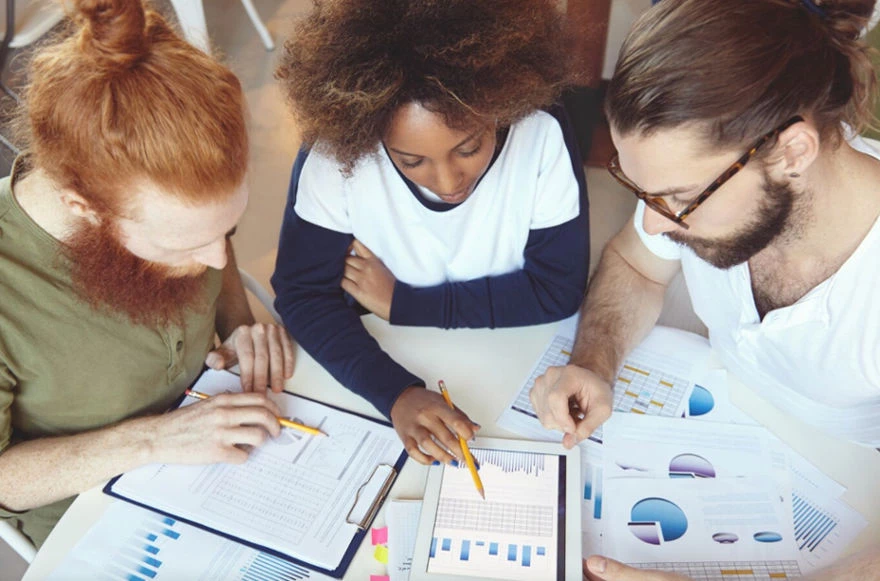 Three team members looking at charts and graphs for CRO & SEO metrics Three team members looking at charts and graphs for CRO & SEO metrics