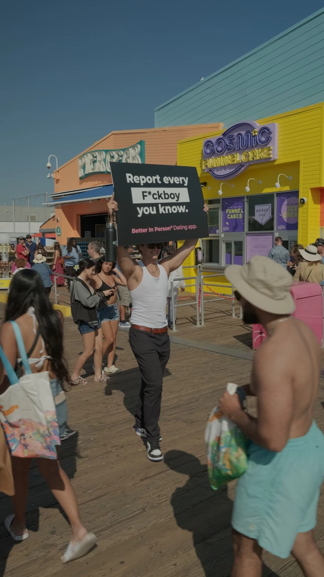 A "f**kboy" walks the crowded street with a Better in Person banner.