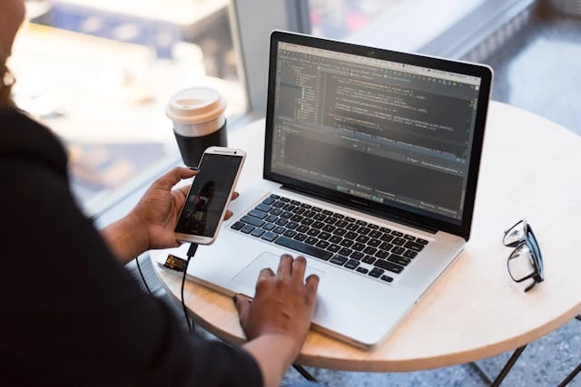 Person with laptop holding phone