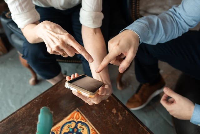 People pointing at mobile phone