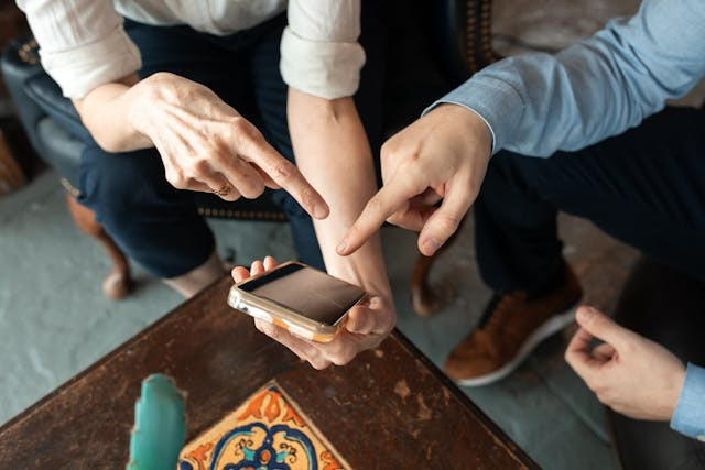 People pointing at mobile phone