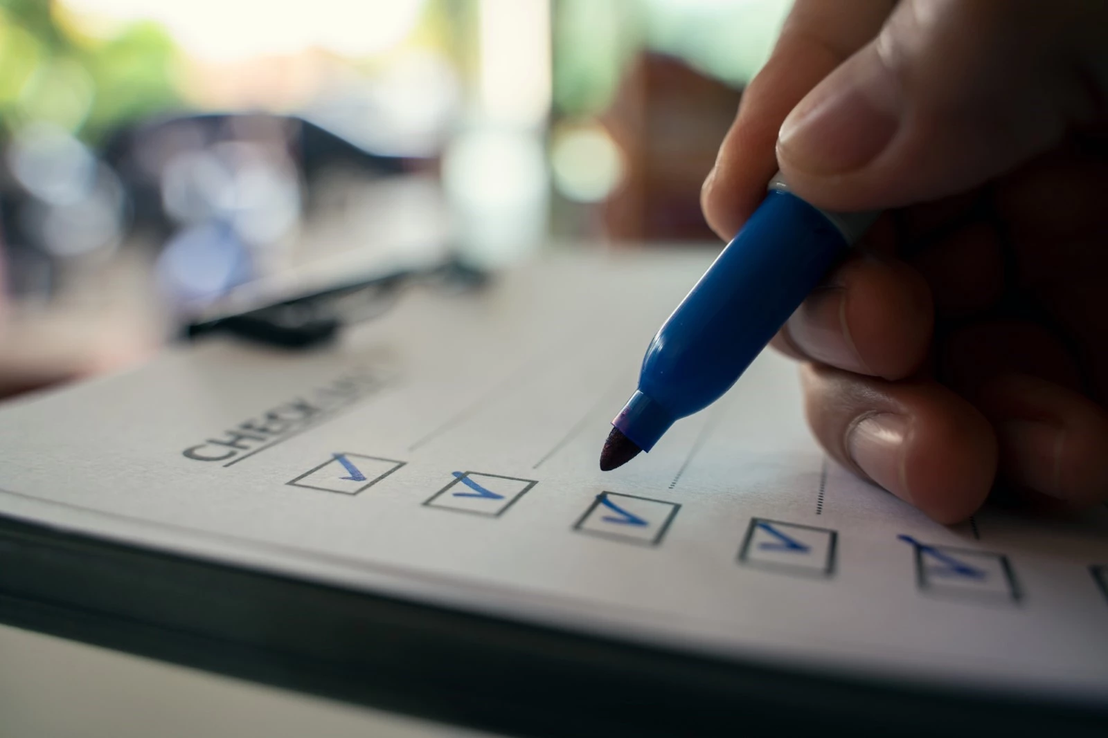 A man uses a blue pen to put check marks on boxes